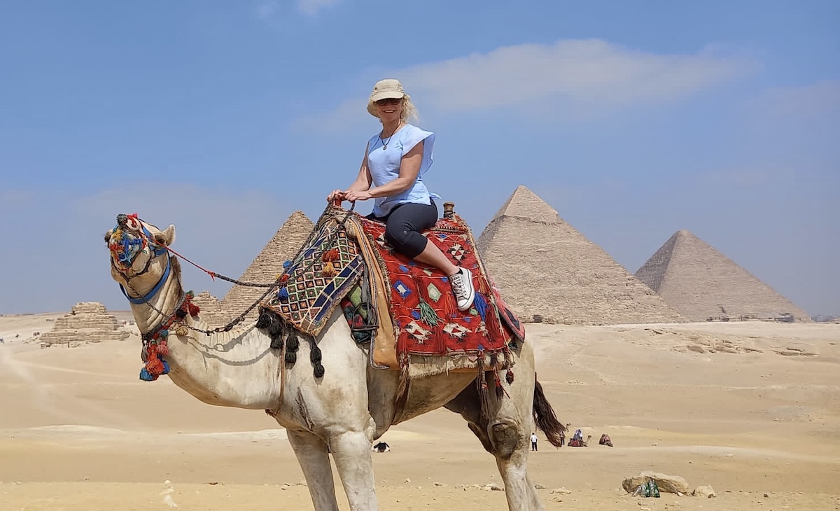 Woman on camel with the great pyramids of giza in the background