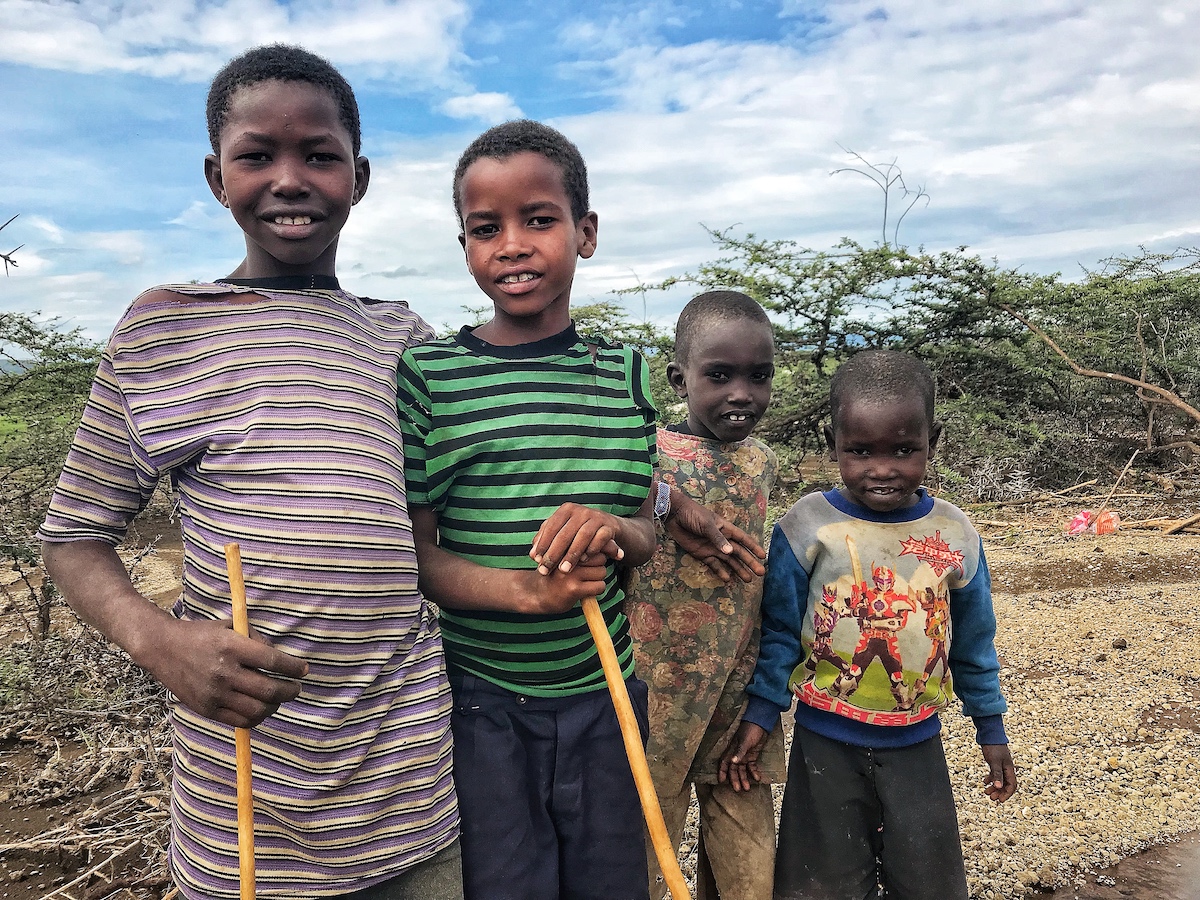 Four sheep herding siblings in Africa holding their herding staffs looking at the camera