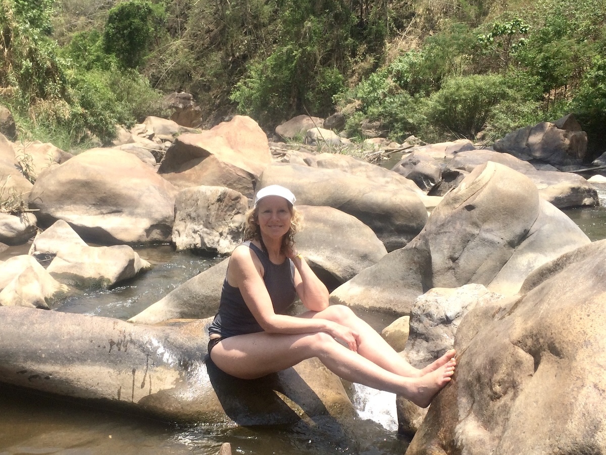 woman sitting on rocks in a stream looking at camera
