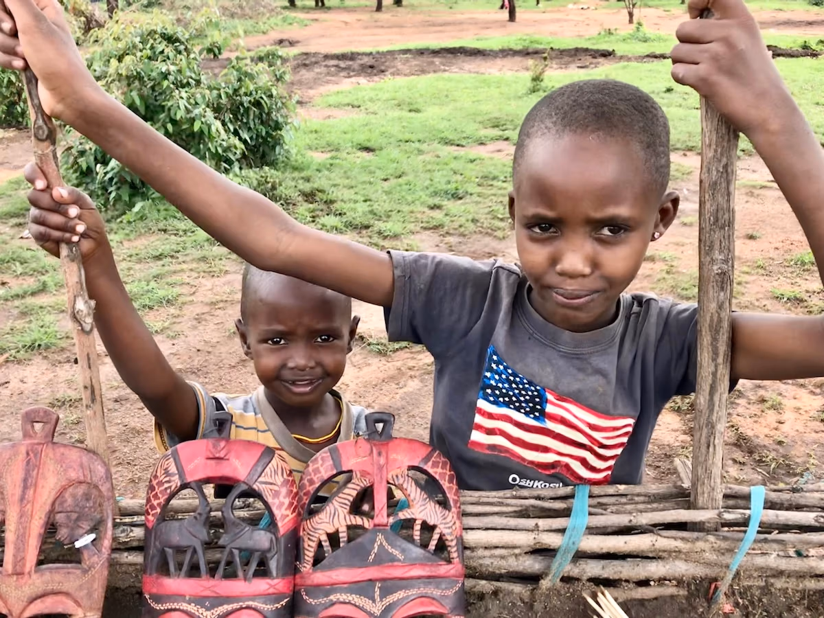 Two children in front of decorative masks