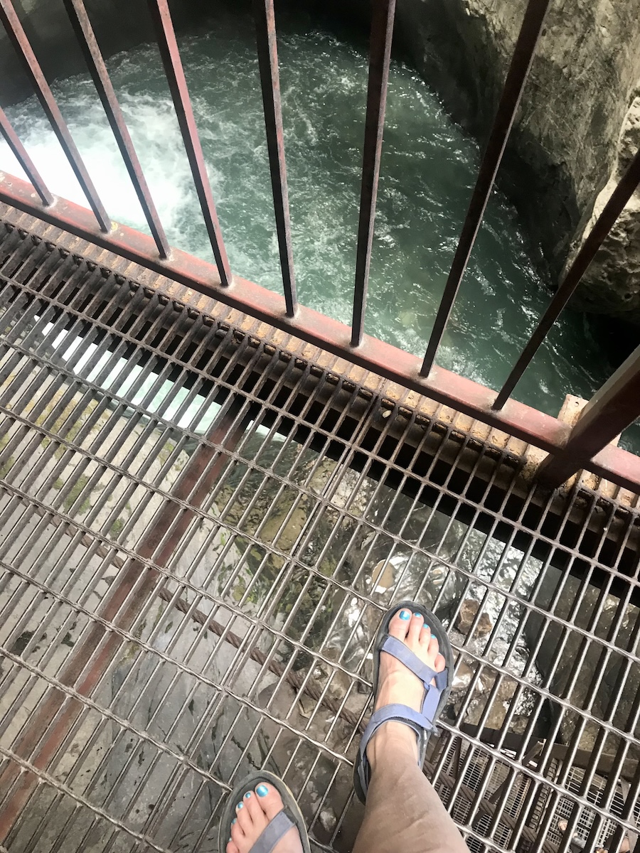 feet on a walkway over the water
