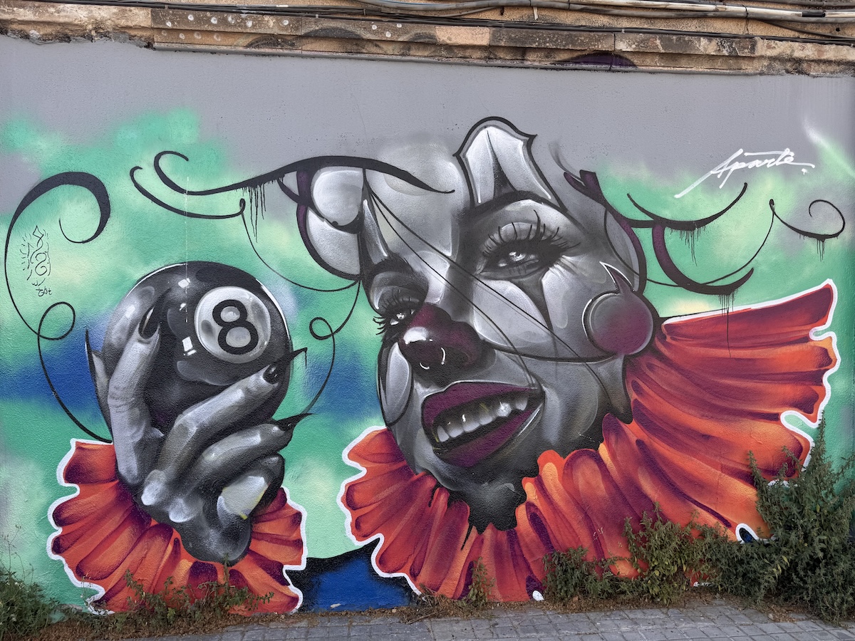 A clown holding an 8 ball on a wall in Barcelona