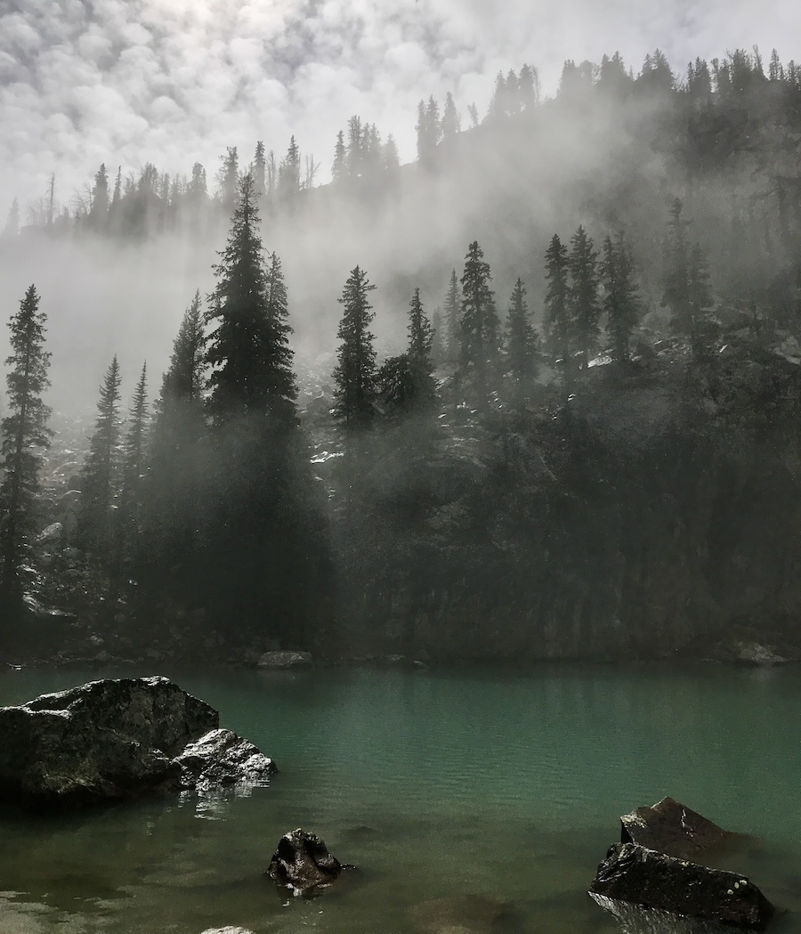 The fog lifting over the trees, lake and mountains