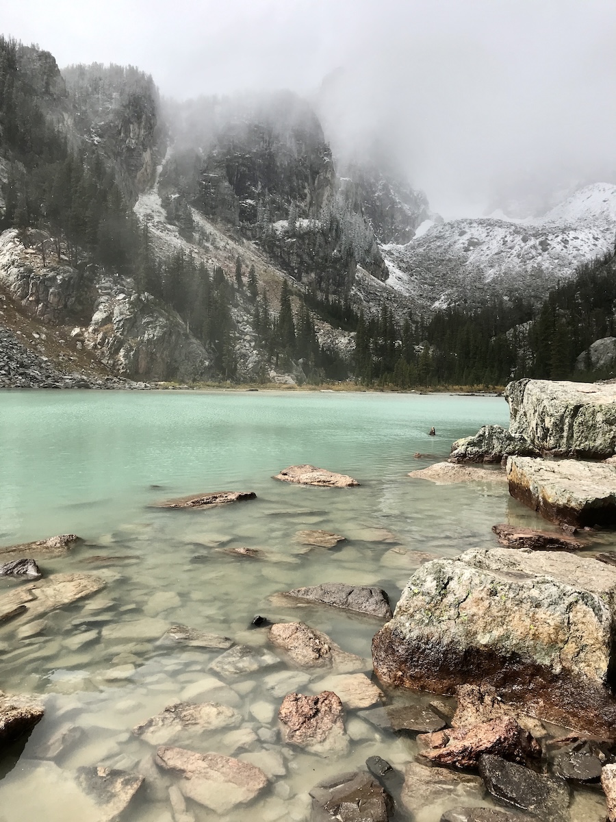 Light green lake with rocks on the edge surrounded by mountains