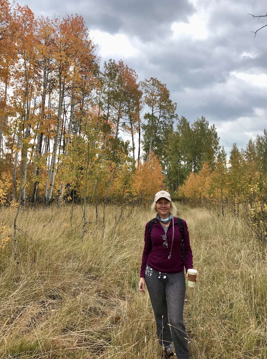 Woman posing in front of Aspen trees that are turning orange