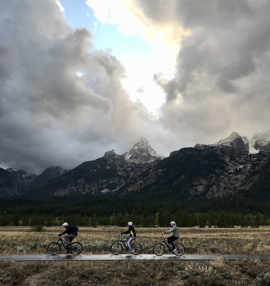 Three bike riders passing in front of grand tetons