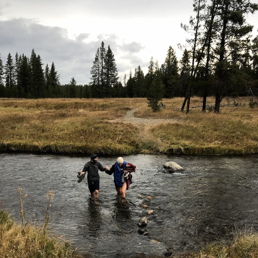 A couple wading through a river