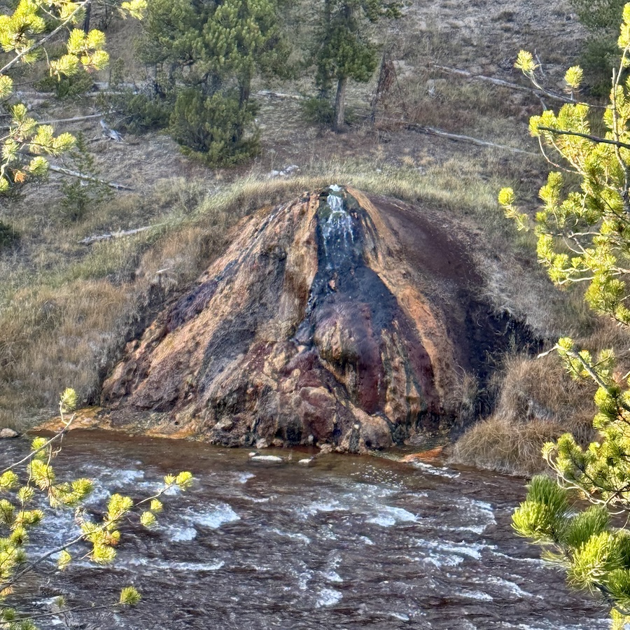 A rust and chocolate colored gurgling thermal cone called Chocolate Pots in Yellowstone