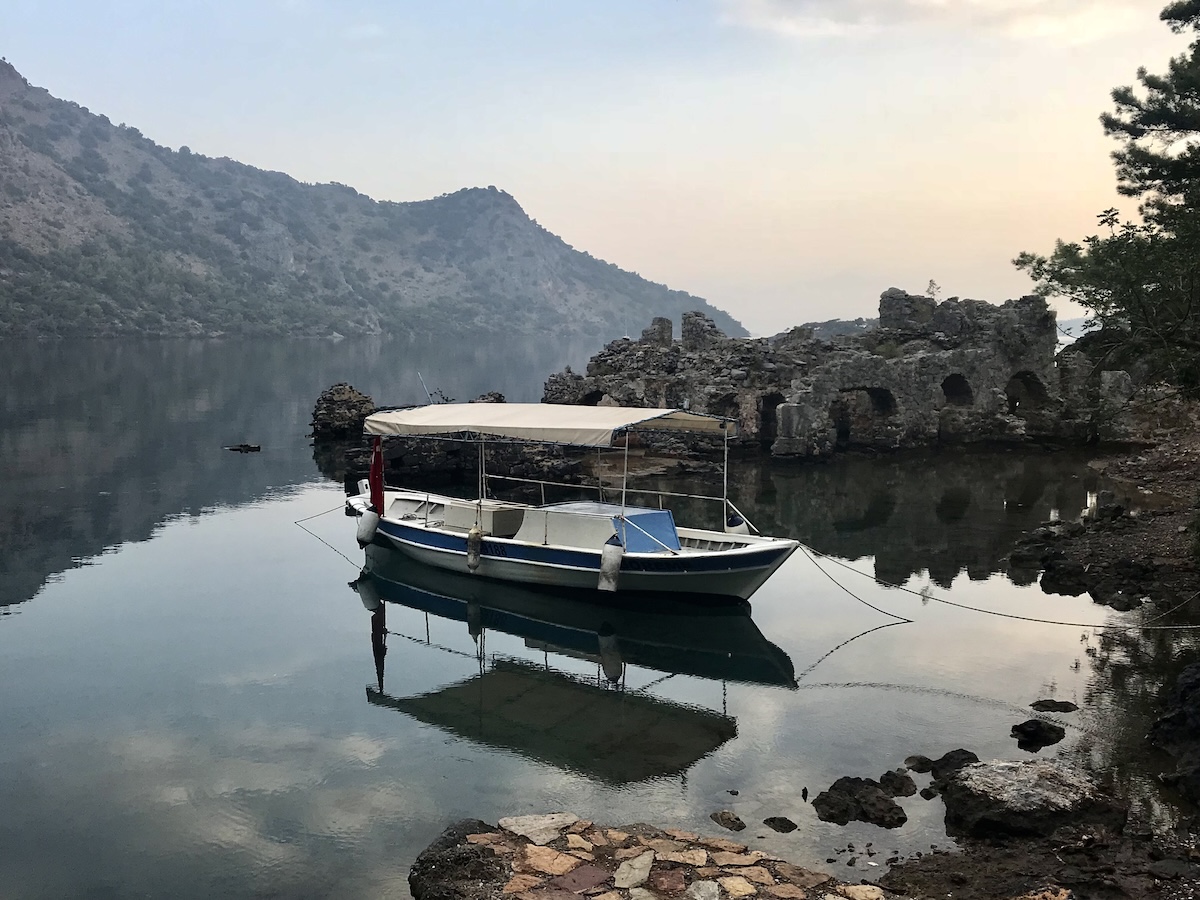 Boat sits on the water surrounded by mountains