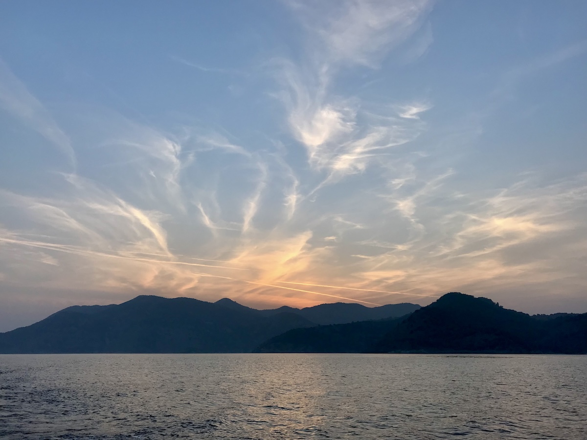 Colorful sunrise with a burst of orange clouds on the Mediterranean Sea over land in the distance