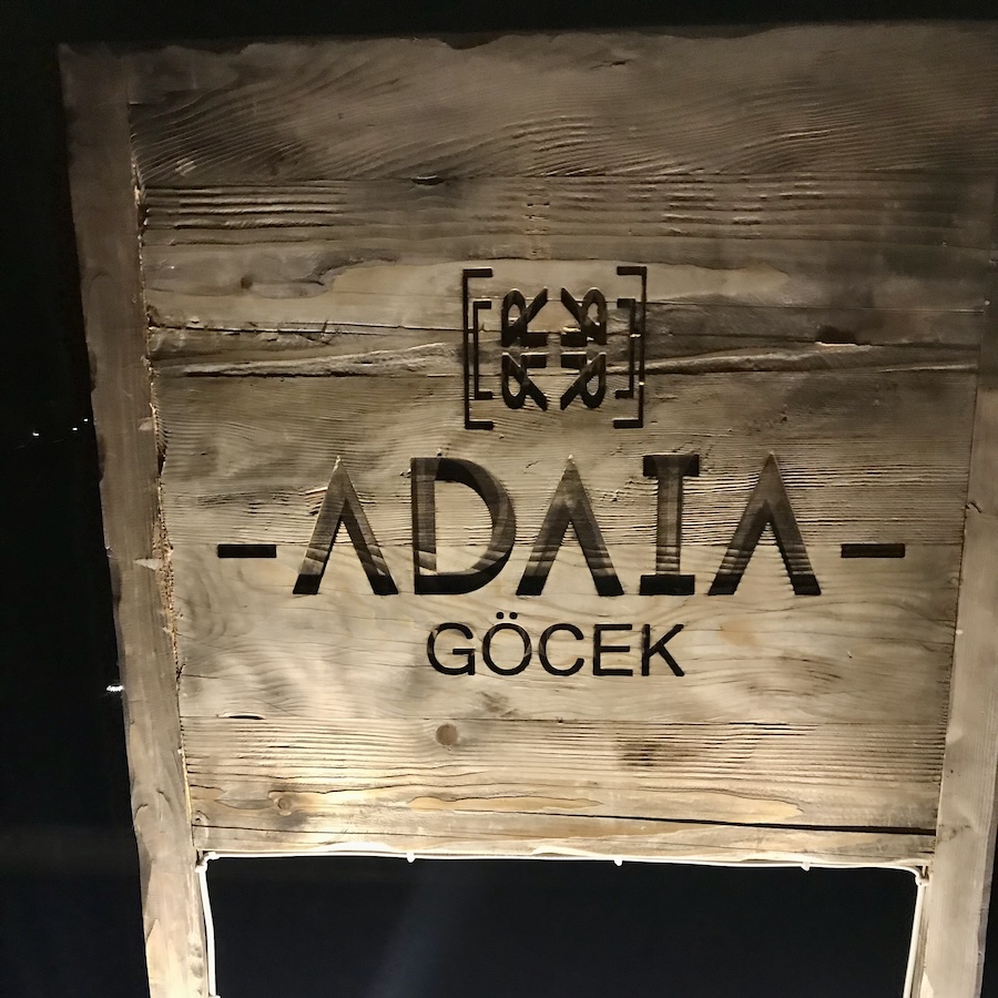 A wooden sign that is carved ADAIA GÖCEK