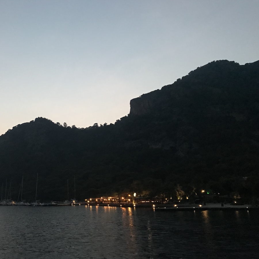 Pulling into a small marina at dusk the lights of the dock nestled at the base of a mountain in Göcek