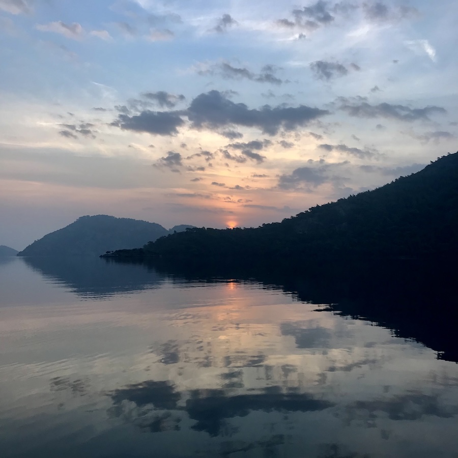 Beautiful colorful sunrise over mountains with clouds reflected in the Med