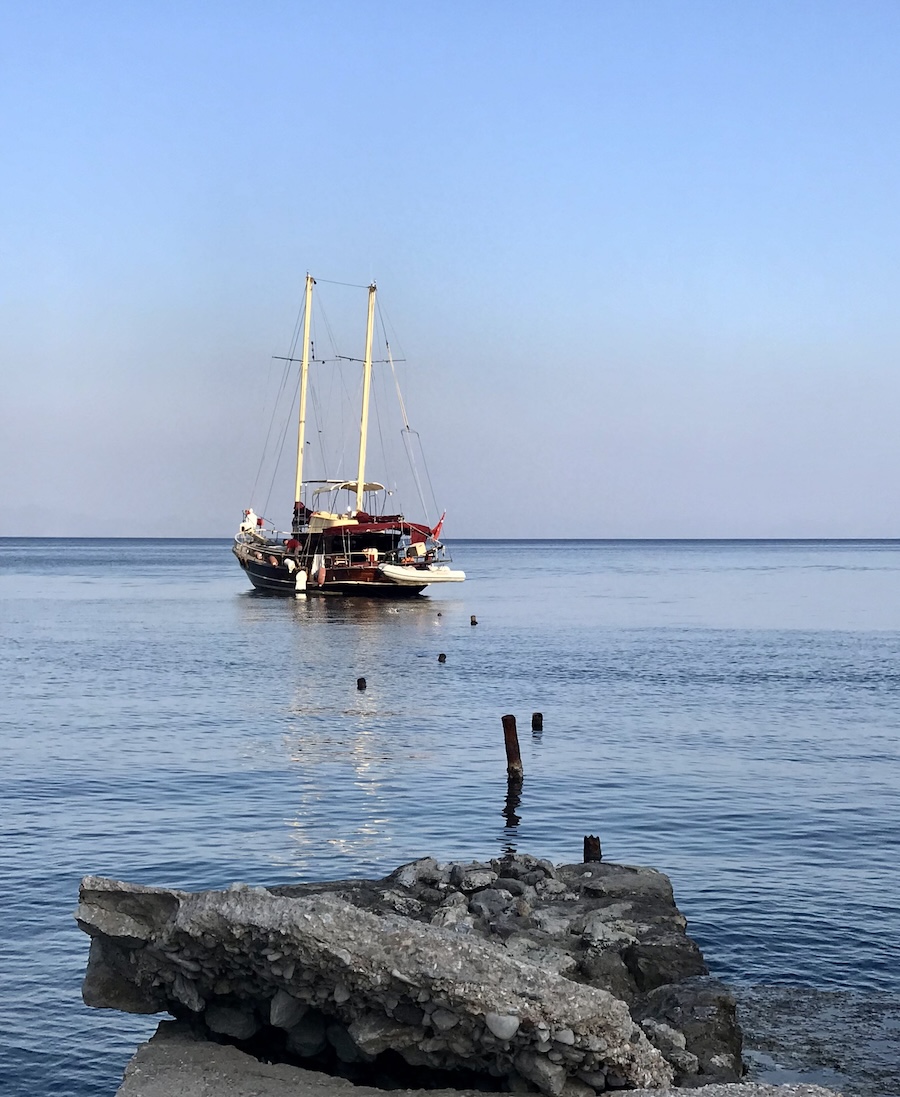 A traditional wooden gulet anchored in a serene turquoise bay along the Aegean coast of Türkiye.