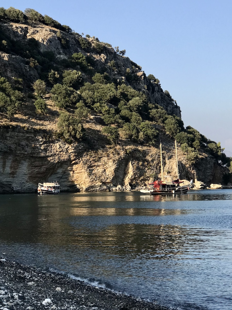 The ancient city of Amos overlooks this serene bay, where our boat is anchored in the crystal-clear waters below.