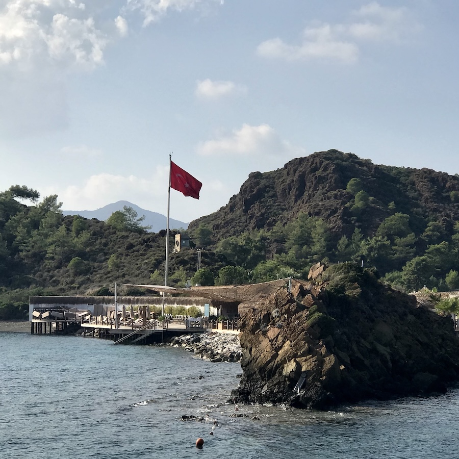 View of beach club and turkish flag nestled in volcanic mountains