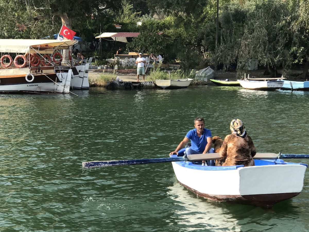 Two locals on a row boat heading away from the shore in Dalyan, Türkiye