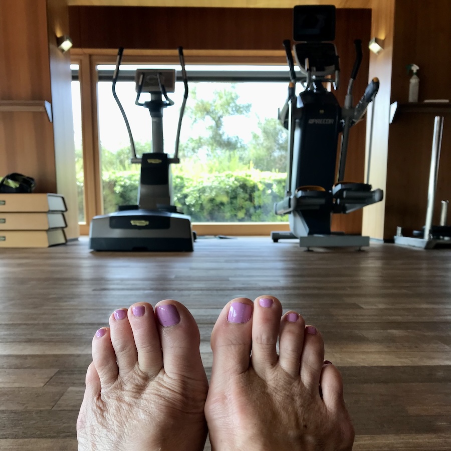 Feet with pink toes on wooden gym floor with equipment in the background