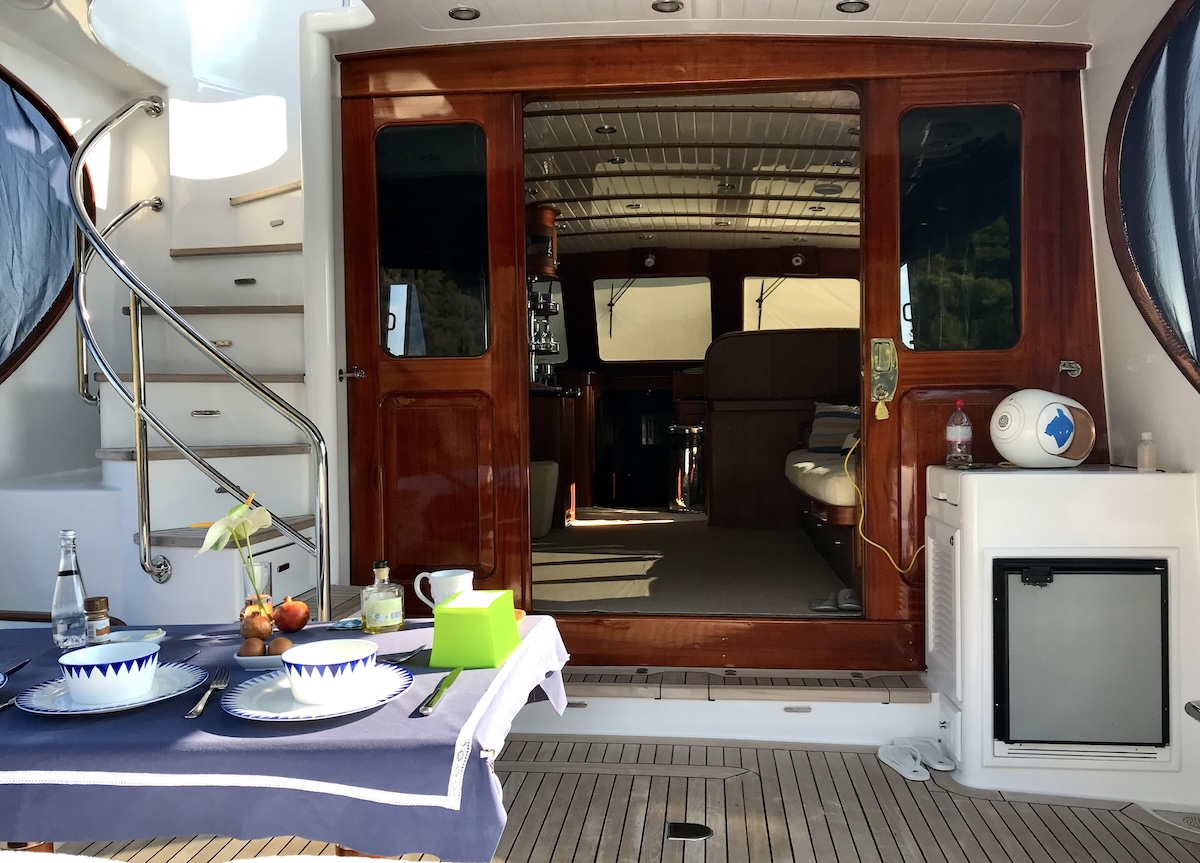 A table is set on a yacht with the wooden doors of the cabin and stairs heading up