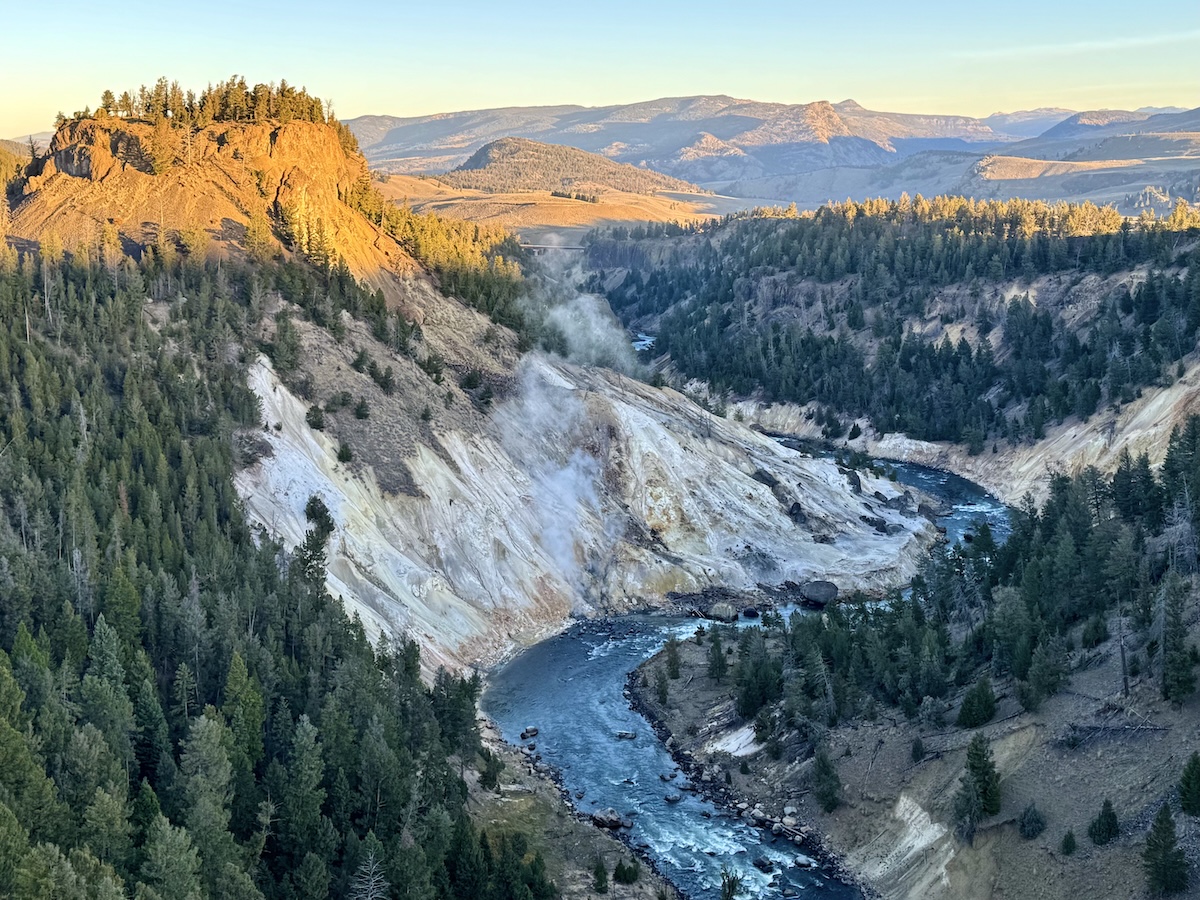 Sunrise hits the tip of a mountain with river flowing and white rock below