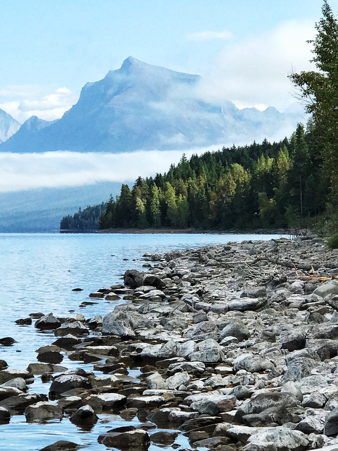 Majestic mountains rise above both clouds and McDonald Lake in Glacier National Park